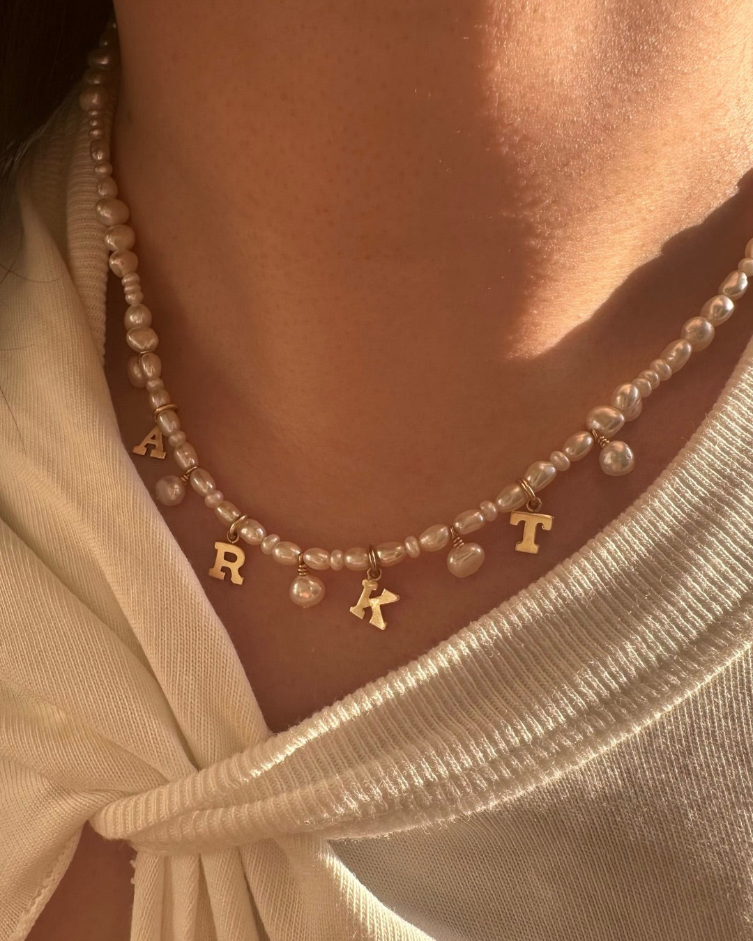 Model wearing gold-filled Classic Pearl Initial Choker with organic freshwater pearls and customisable initials, puffy heart or mini pearl charms.