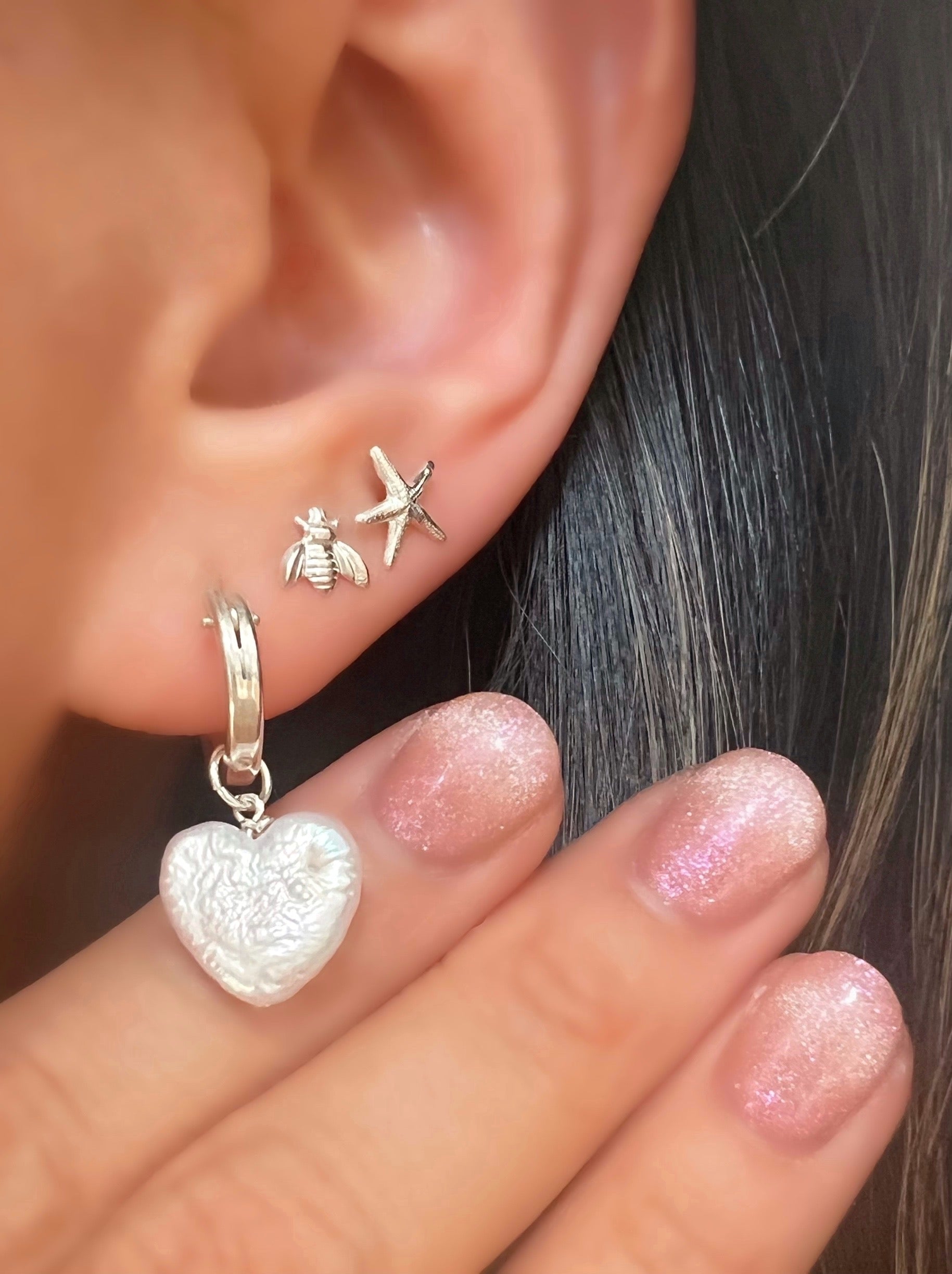 Sterling Silver Pearl Heart Charms on a Silver Hoop Earrings and Silver Bee and Starfish Stud Earring on a model