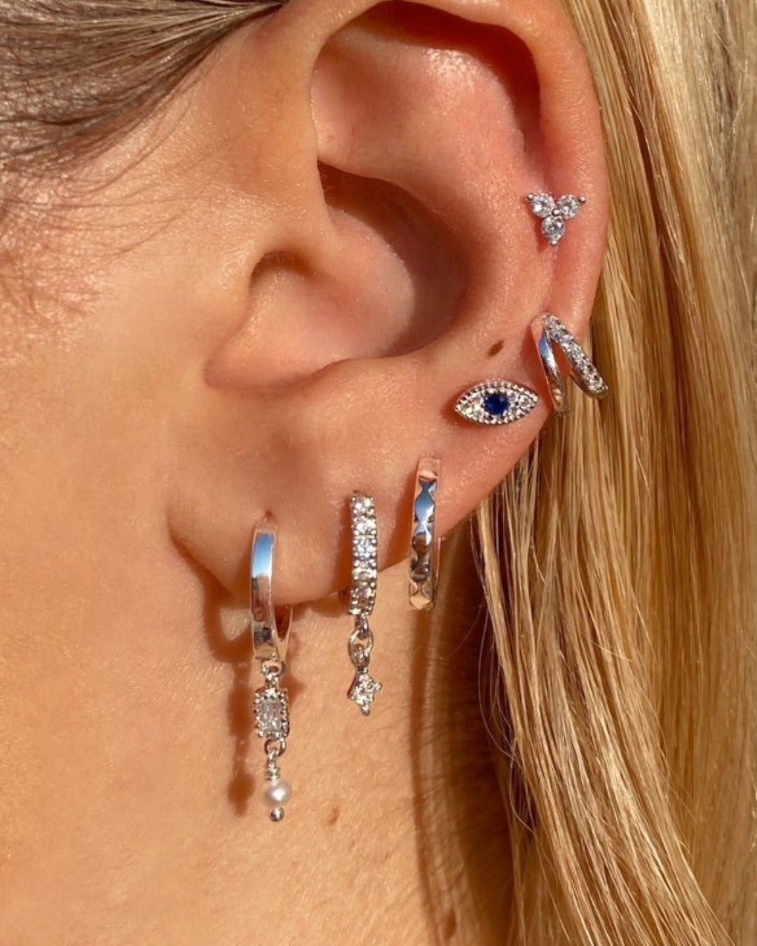 Reversible sterling silver flatback stud earring with a front trio of cubic zirconia crystals and a back trio of polished silver balls, photographed on a model.