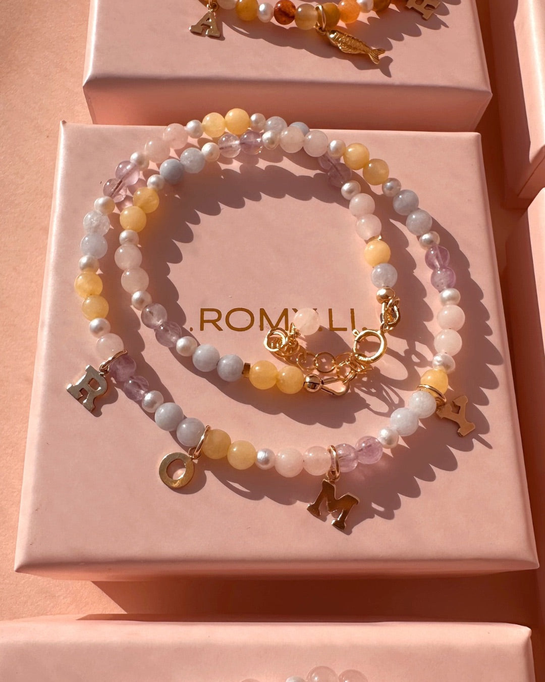 Pastel Gem Charm Necklace with charms on a Romyli jewellery gift box.