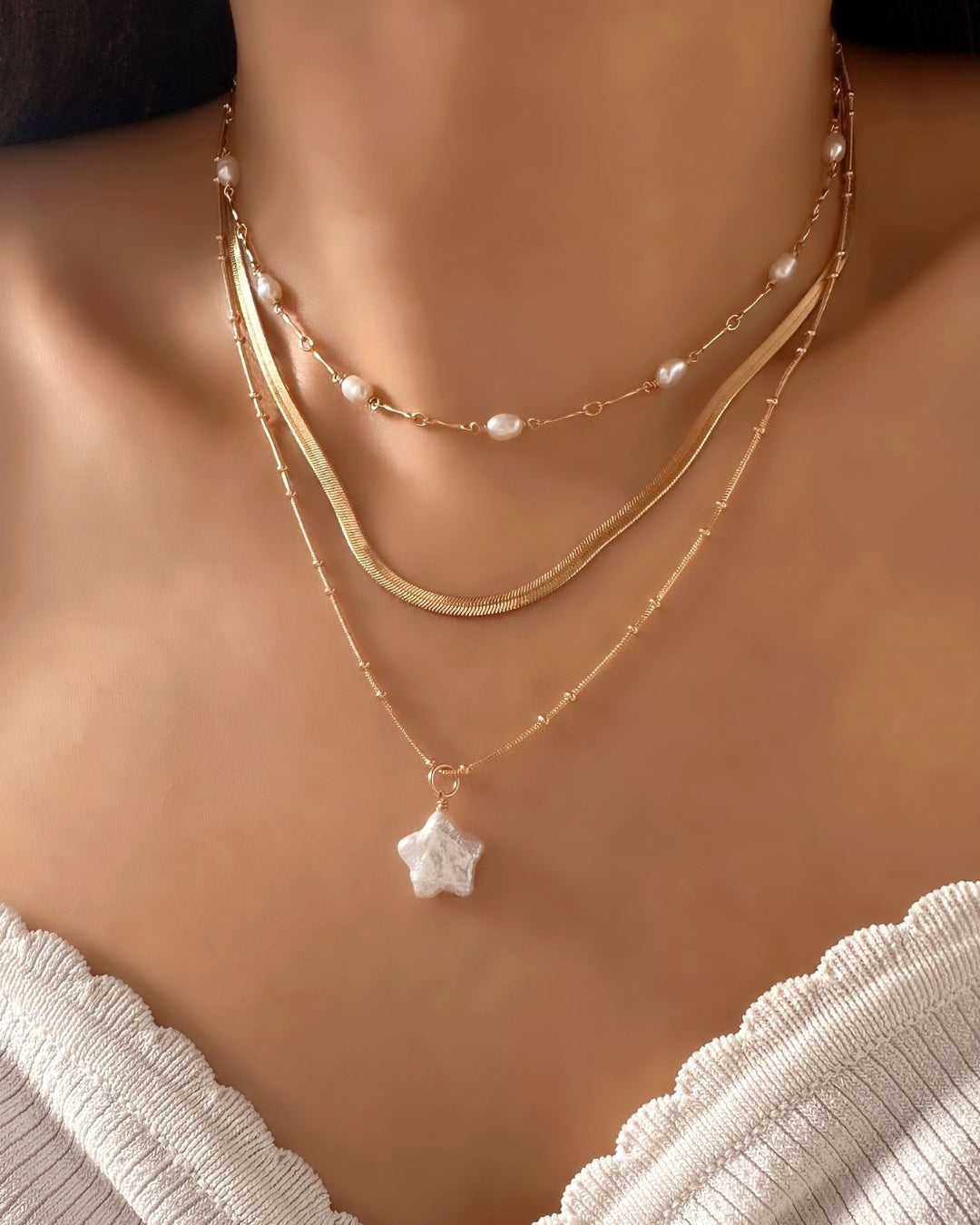 Model wearing Gold Cosmic Star Pearl Necklace, stacked with Opalene Pearl Choker and Mini Serpentine Necklace.