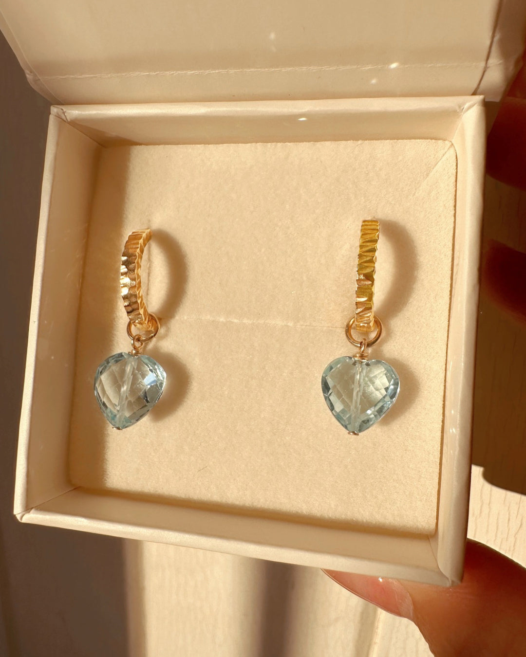Close-up of a genuine topaz heart earring charm in 14k gold fill, approximately 10mm in size, designed for mix-and-match styling. Light blue gemstone symbolising clarity, strength, and joy, compatible with all hoops in the Mix and Match Earrings collection.