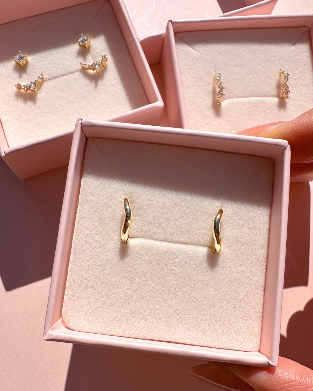 Gold sculptural huggie earrings with organic curved design in a Romyli jewellery box