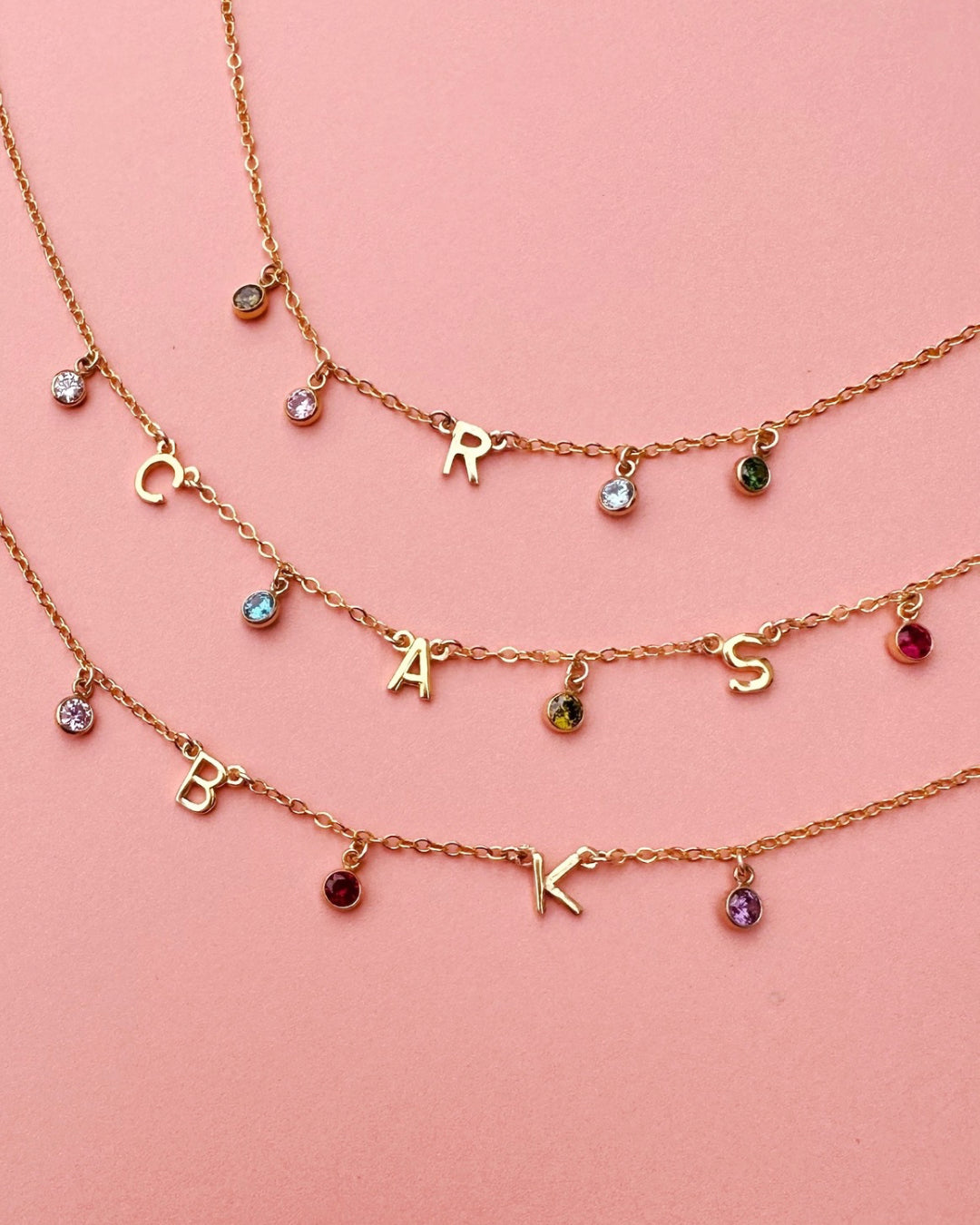 A delicate gold initial birthstone bracelet, customisable with up to 9 initials and birthstones, elegantly set on a fine gold chain. A timeless and meaningful piece for everyday wear and gifting.