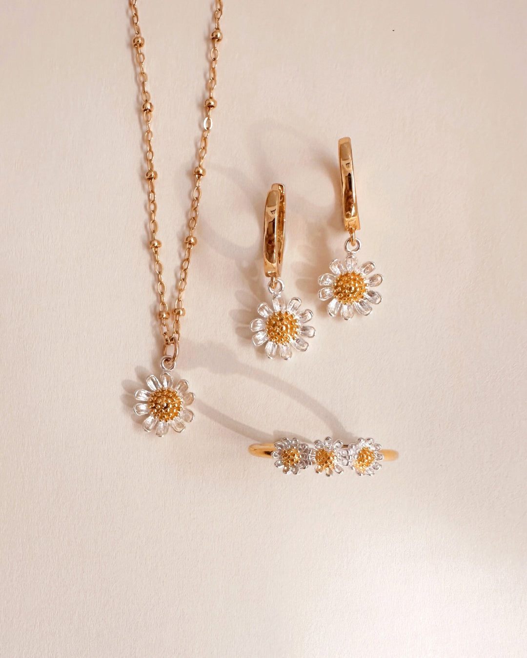 Flatlay of Romyli’s Daisy Chain Ring, a dainty adjustable gold vermeil ring with three two-tone daisy motifs, perfect for everyday wear.