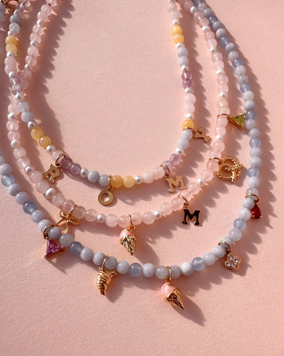 Gemstone charm necklace with charms on a pink background