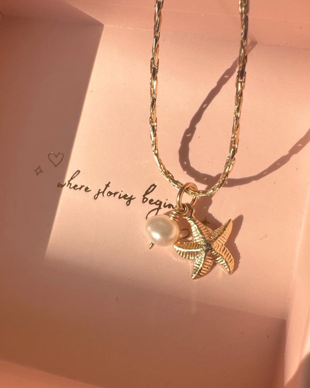 Close up of gold starfish and pearl charm necklace on dainty gold chain. Made in Australia