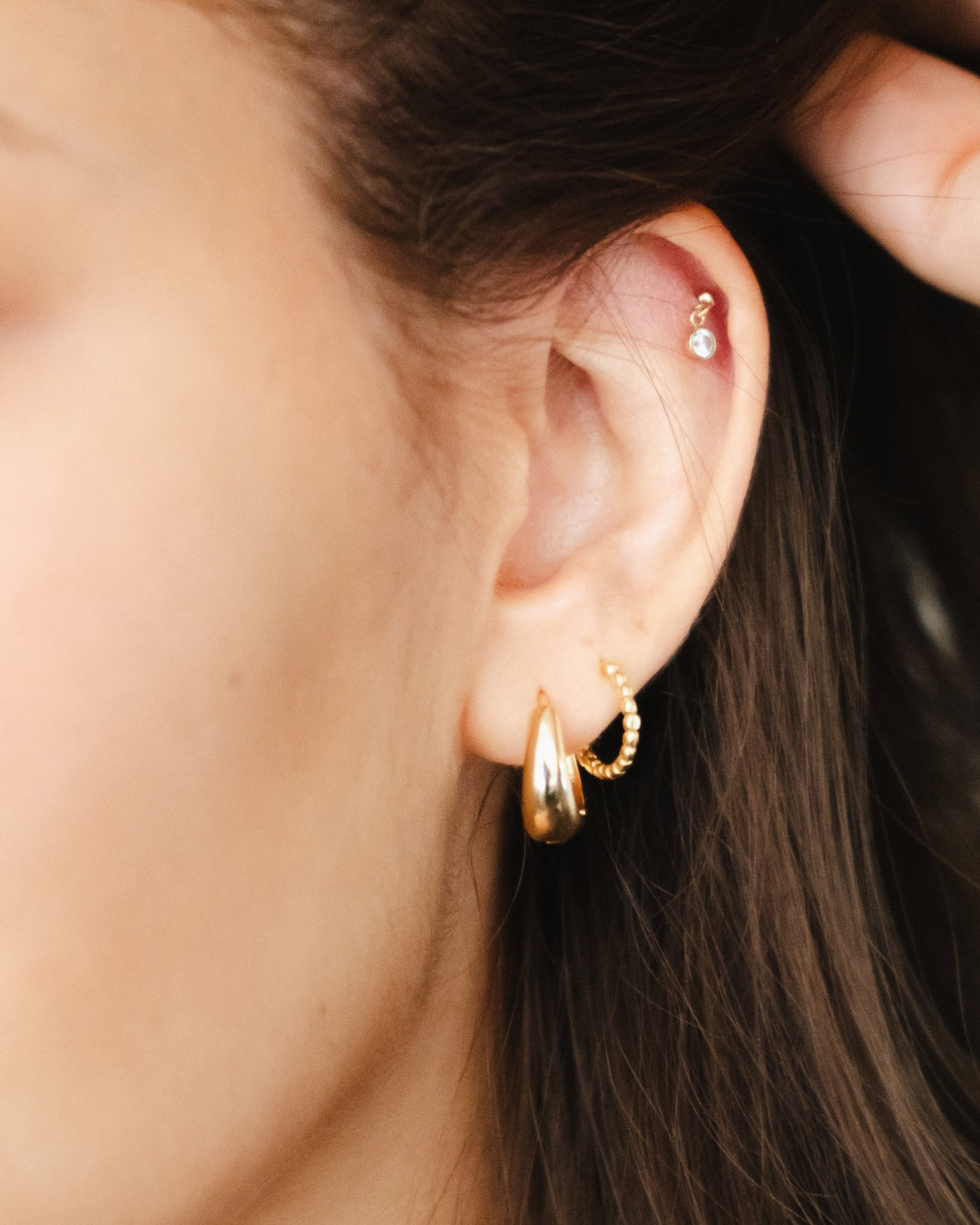 Gold chunky dome Huggie hoop earrings on a model