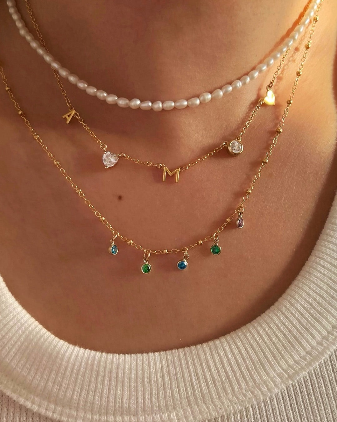 Model wearing a personalised gold petite birthstone necklace with dainty cubic zirconia charms on a delicate gold fill chain