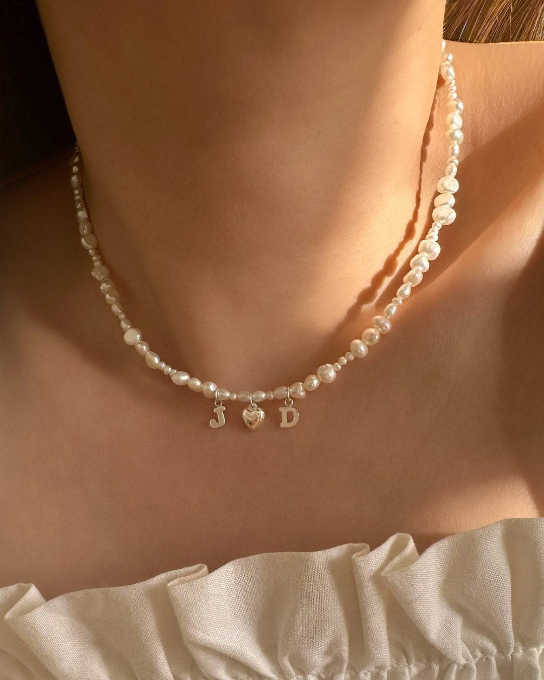 Model wearing Sterling silver Classic Pearl Initial Choker with organic freshwater pearls and 2 initial letters and a puffy heart charm.