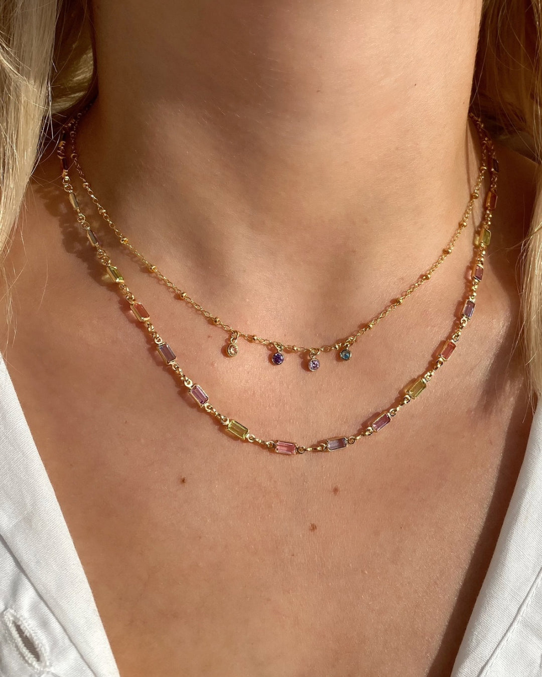 Model wearing a personalised gold petite birthstone necklace with dainty cubic zirconia charms on a delicate gold fill chain