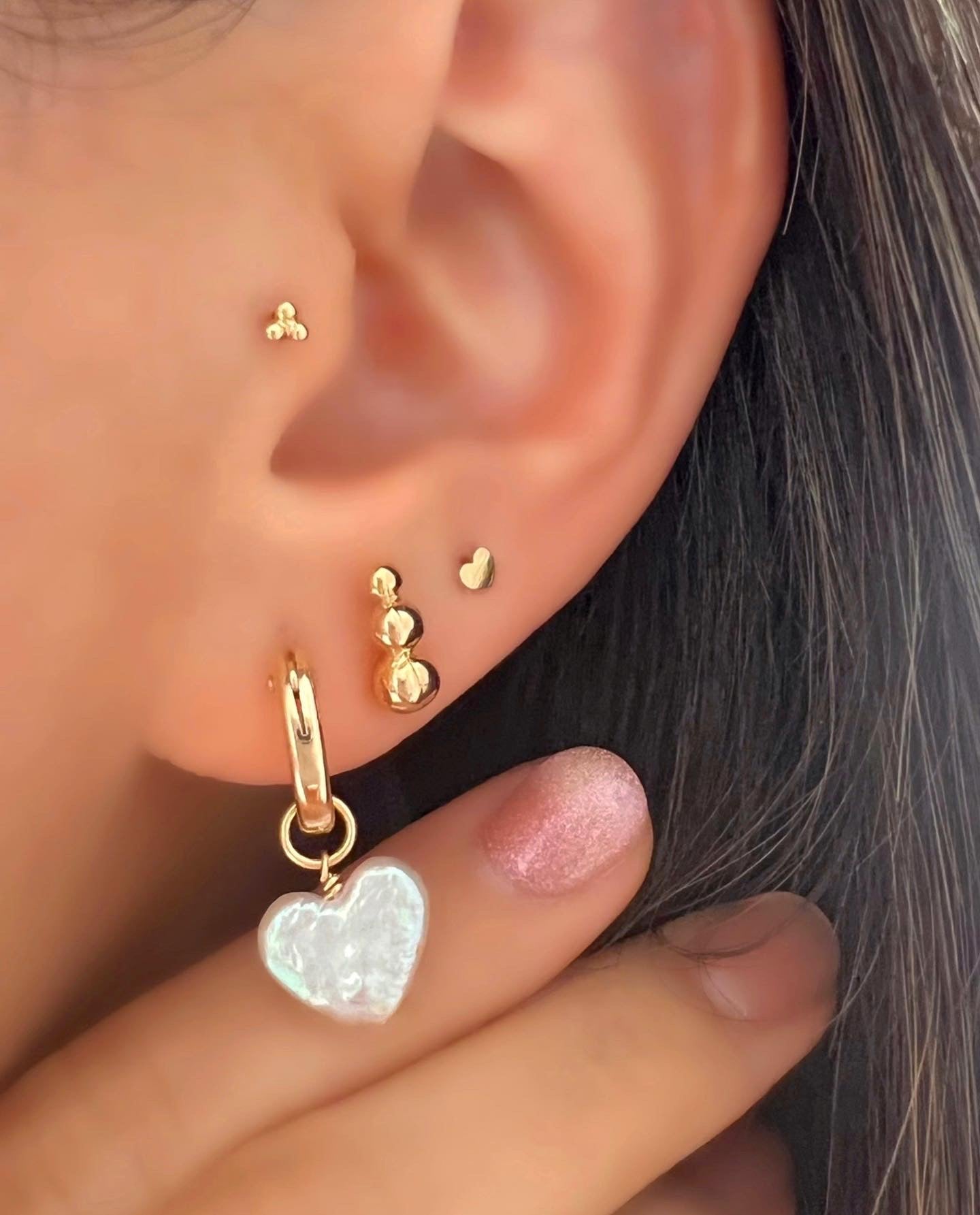 14k yellow gold fill hoops with freshwater pearl heart charm earrings on a model