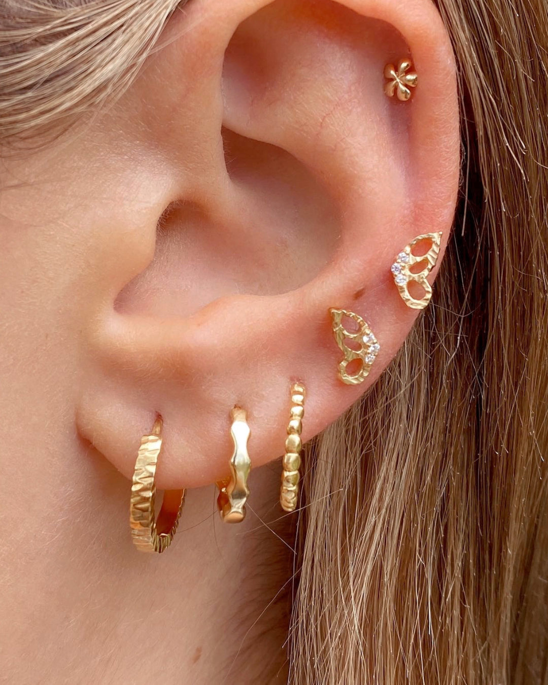 Gold butterfly flutter stud earrings stacked with gold hoop earrings and solid gold Flatback studs on a model