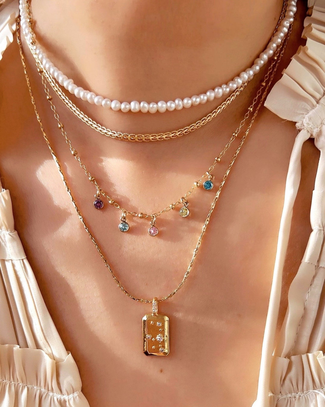 Model wearing a personalised gold petite birthstone necklace with dainty cubic zirconia charms on a delicate gold fill chain