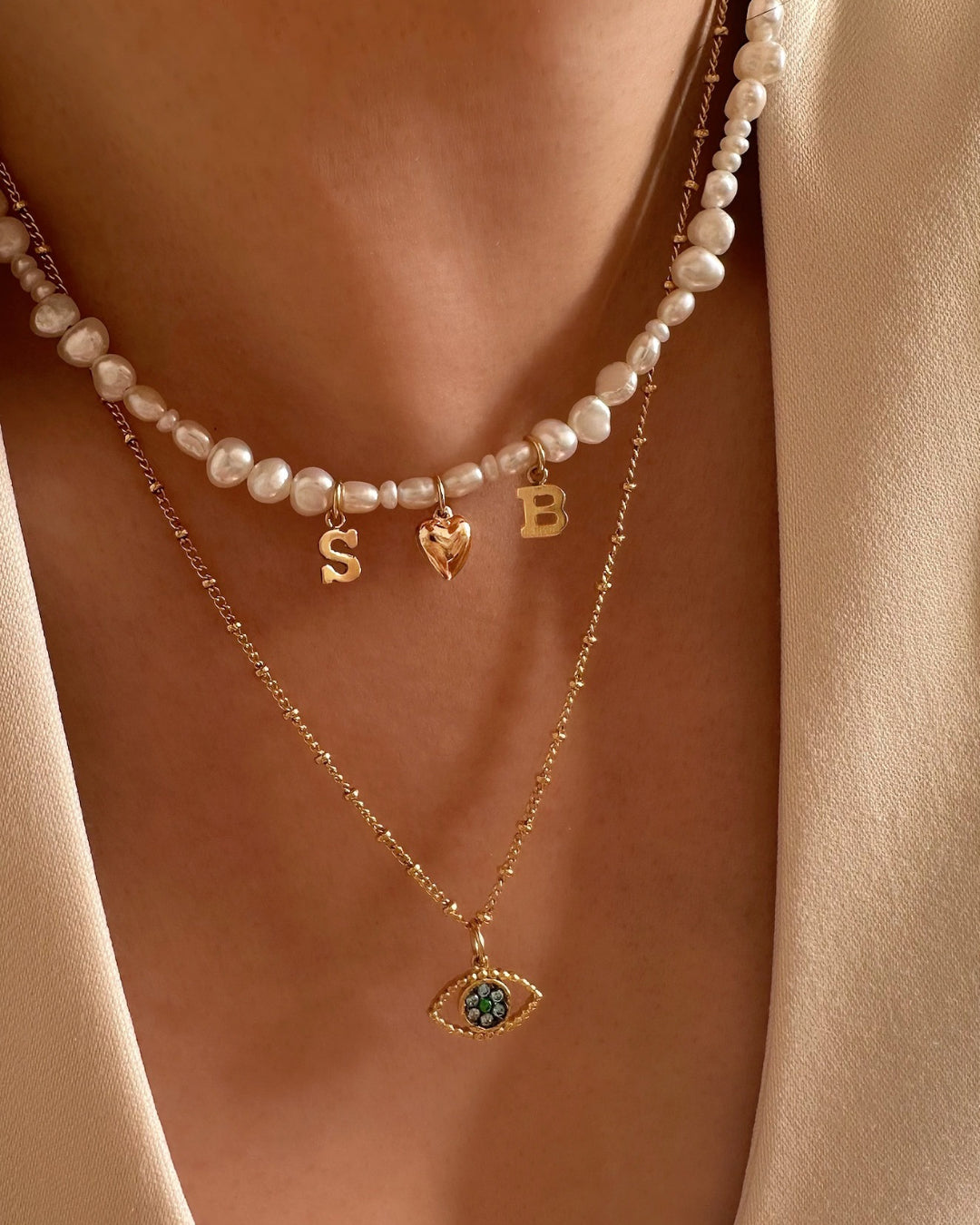 Model wearing Gold-filled Classic Pearl Initial Choker with organic freshwater pearls and customisable initials and puffy heart charm, layered with Evil Eye Talisman Necklace