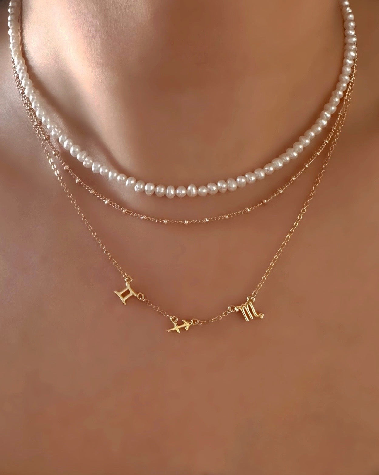 14k gold fill small zodiac sign necklaces layered with pearl choker on a model. Made in Australia.
