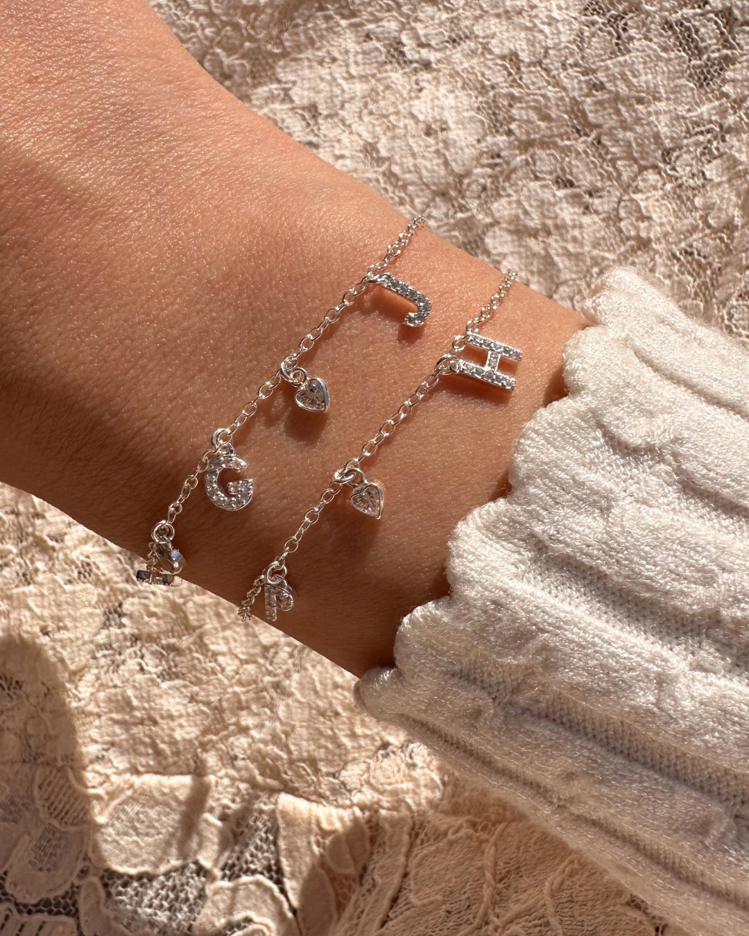 Model wearing silver pavé initial bracelet with sparkling custom letters and bezel heart charms, dainty personalised sterling silver jewellery