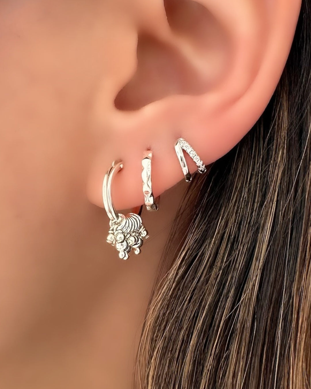 Sterling Silver Cluster Hoop Earrings on a model. Stacked with Silver Vela Hoops and Silver Mirra Huggies