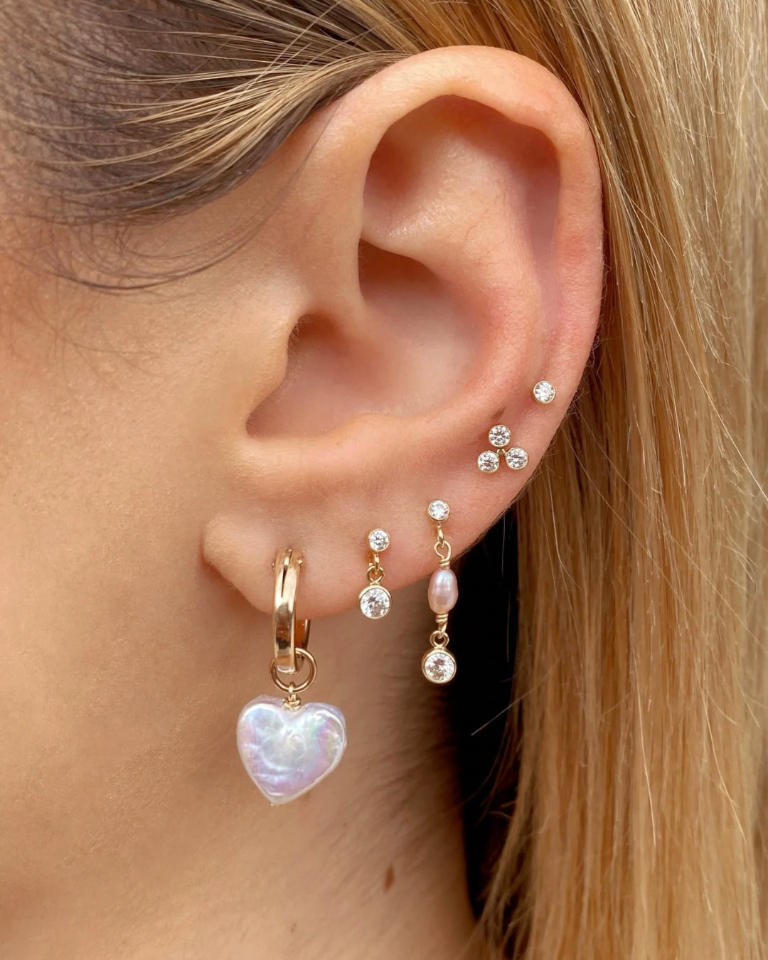 14k yellow gold fill hoops with freshwater pearl heart charm earrings on a model