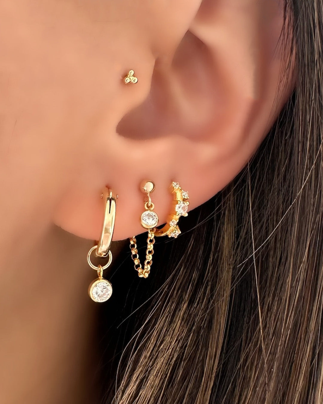 Model wearing 14k gold filled bezel gem chain stud earring featuring a tiny white cubic zirconia crystal. Delicate design suitable for lobe or helix piercing.
