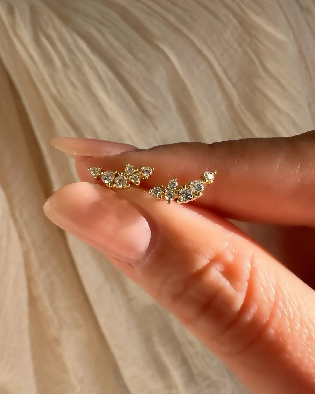 Gold climber stud earrings with a curved linear cluster of brilliant round crystals