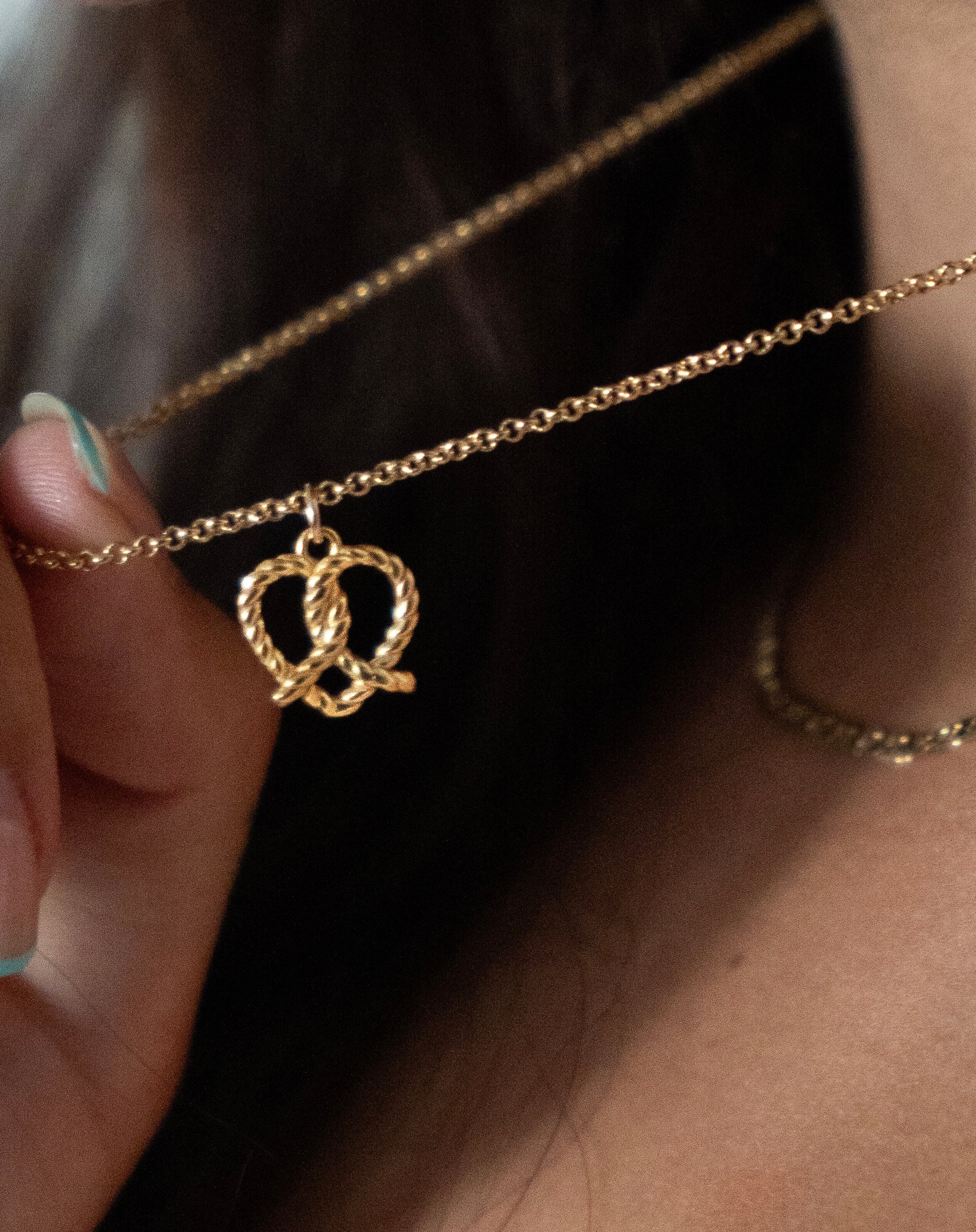 14k yellow gold fill pretzel heart pendant on a gold Rolo necklace chain on a model