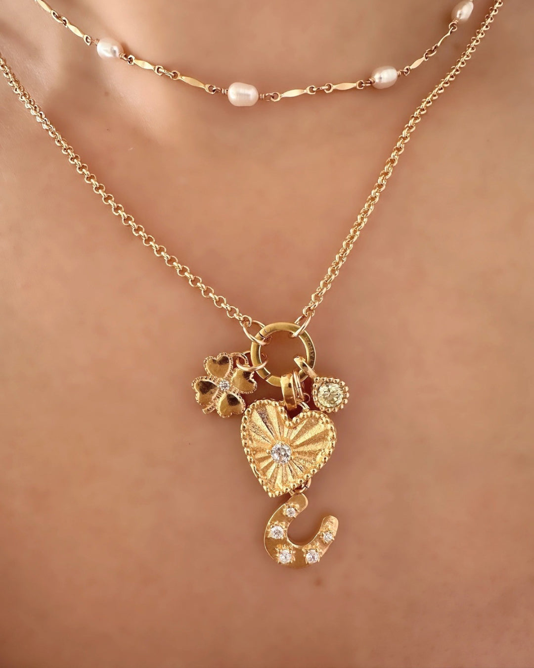 Heart Token Pendant with white cubic zirconia crystal centre, sunray etching, and milgrain detail. Paired with Romyli’s gold Petite Rolo Chain, Clover Pendant, Horseshoe Pendant, and March Aquamarine Birthstone Pendant. All styled inside a Romyli jewellery gift box.