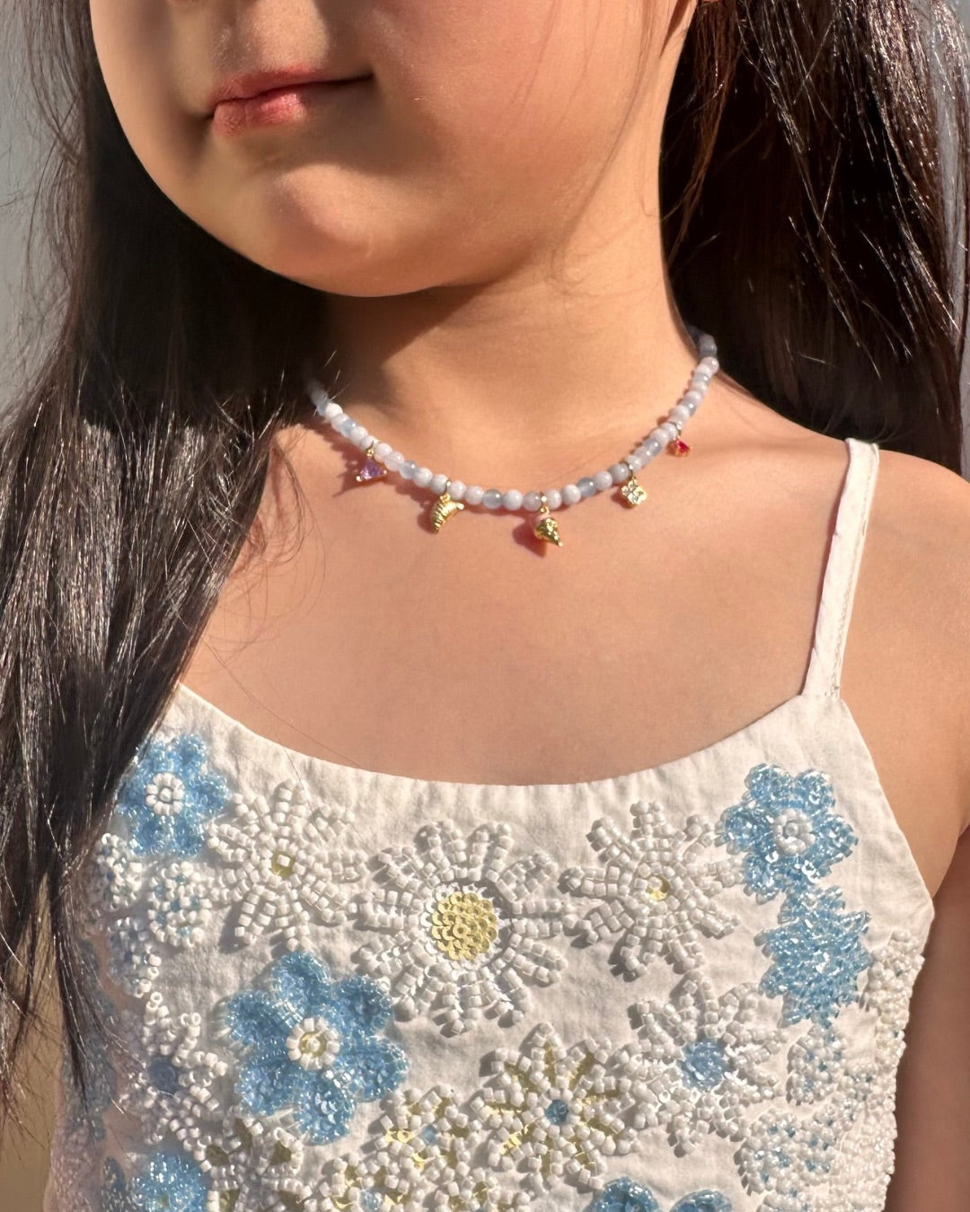Close-up of a child wearing an aquamarine charm necklace.