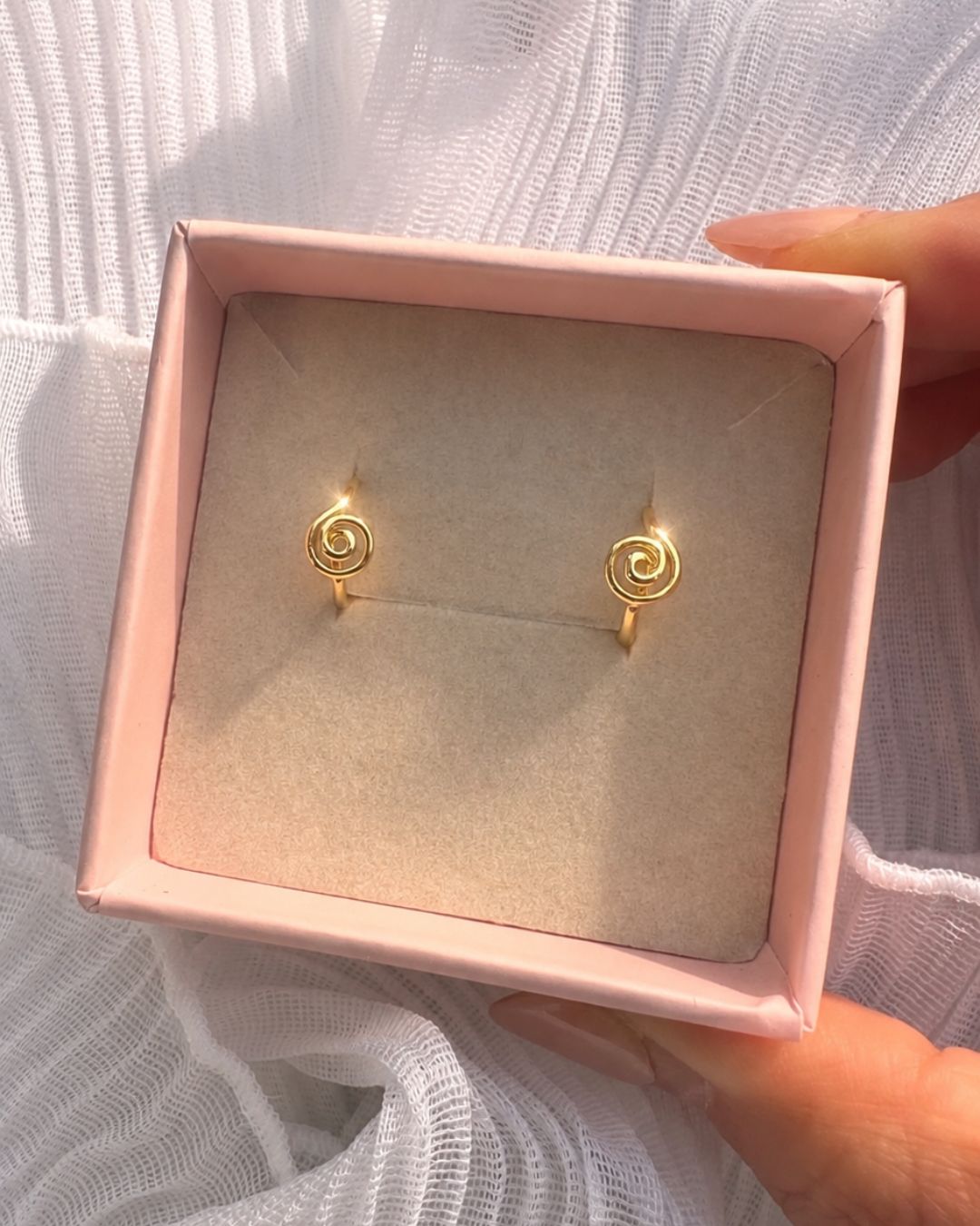 Gold spiral Huggie hoops in a pink romyli jewellery box