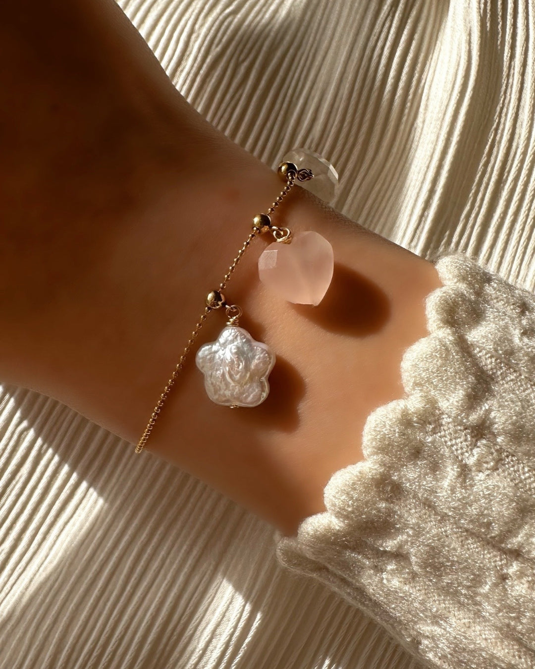 Rose Quartz Heart Charm on a Charm Story Cable Chain Bracelet, stacked with meaningful gold and semi precious charms on a model.