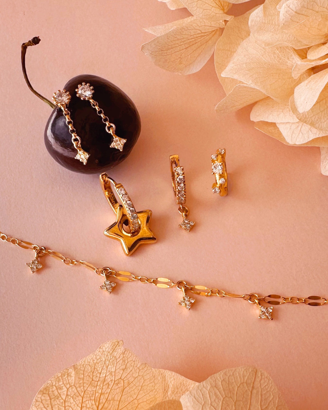 Flatlay of Starfall stud earrings, stellar cluster Huggies and Starfall charm Huggies