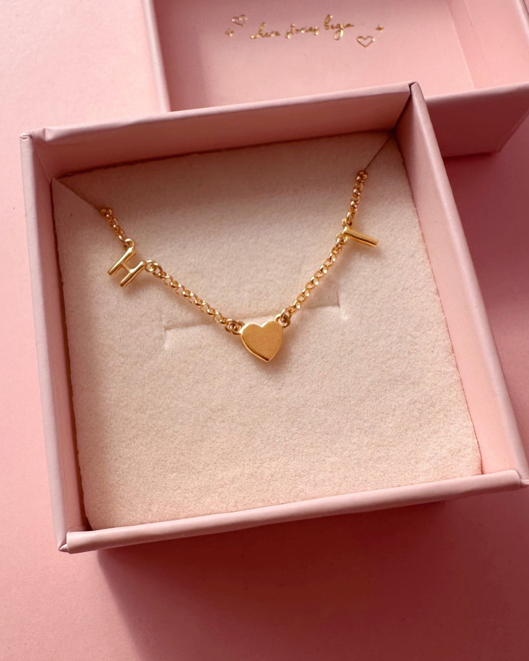 Gold-filled necklace with 2 letter charms and 1 gold heart charms evenly spaced on a petite rolo chain in a Romyli gift box