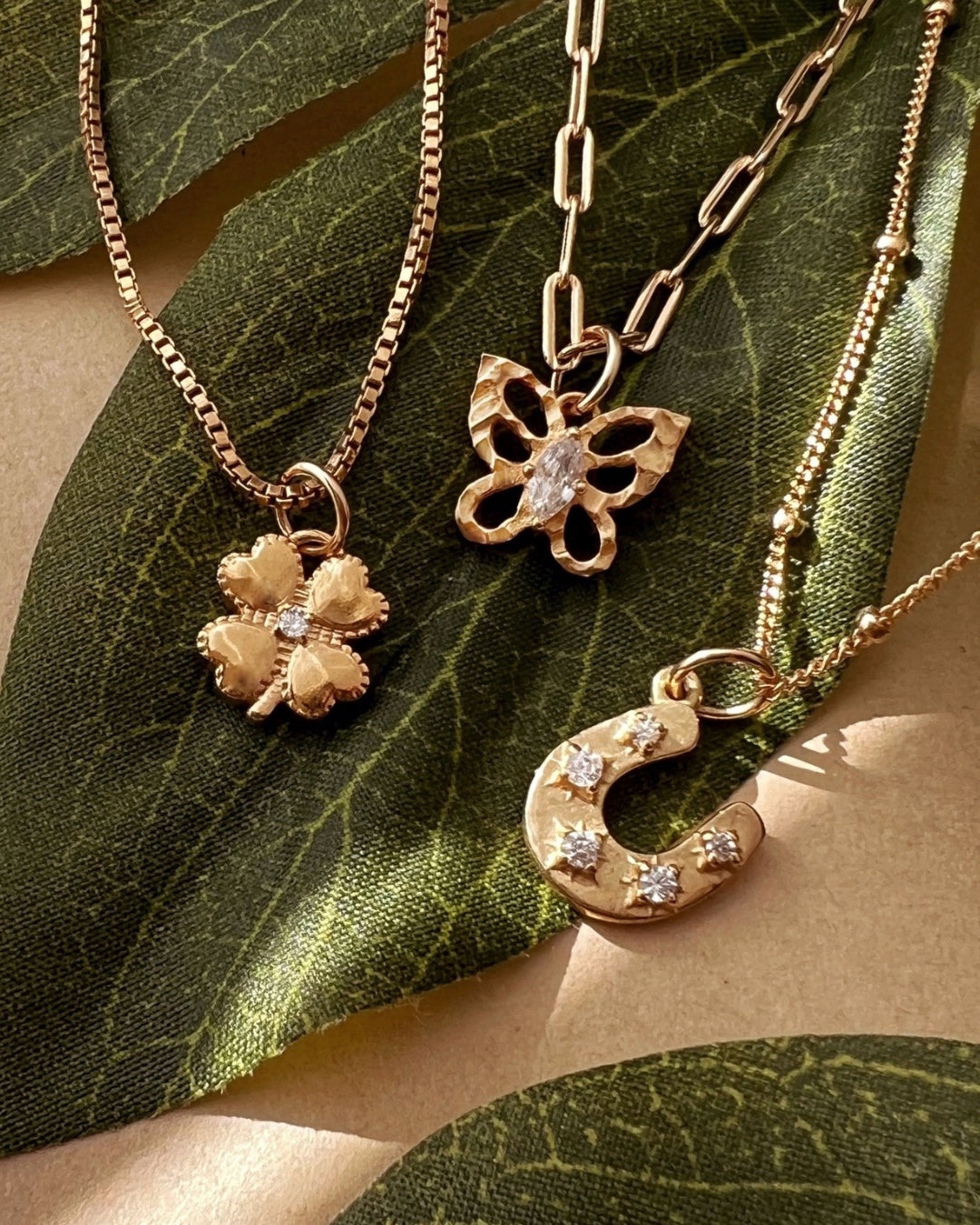 Yellow gold fill box chain necklace paired with clover pendant, paperclip chain necklace paired with the textured butterfly pendant and satellite chain necklace paired with the horseshoe pendant.