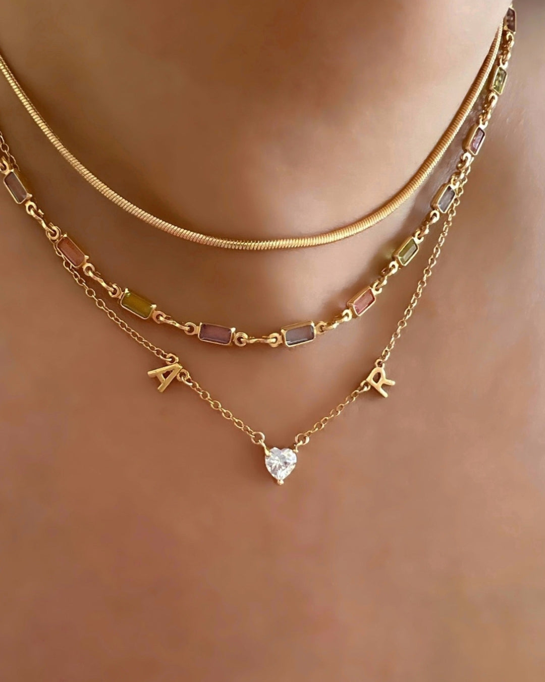 Gold Petite Initial Necklace with Letter A, Heart Gem, Letter R on a model