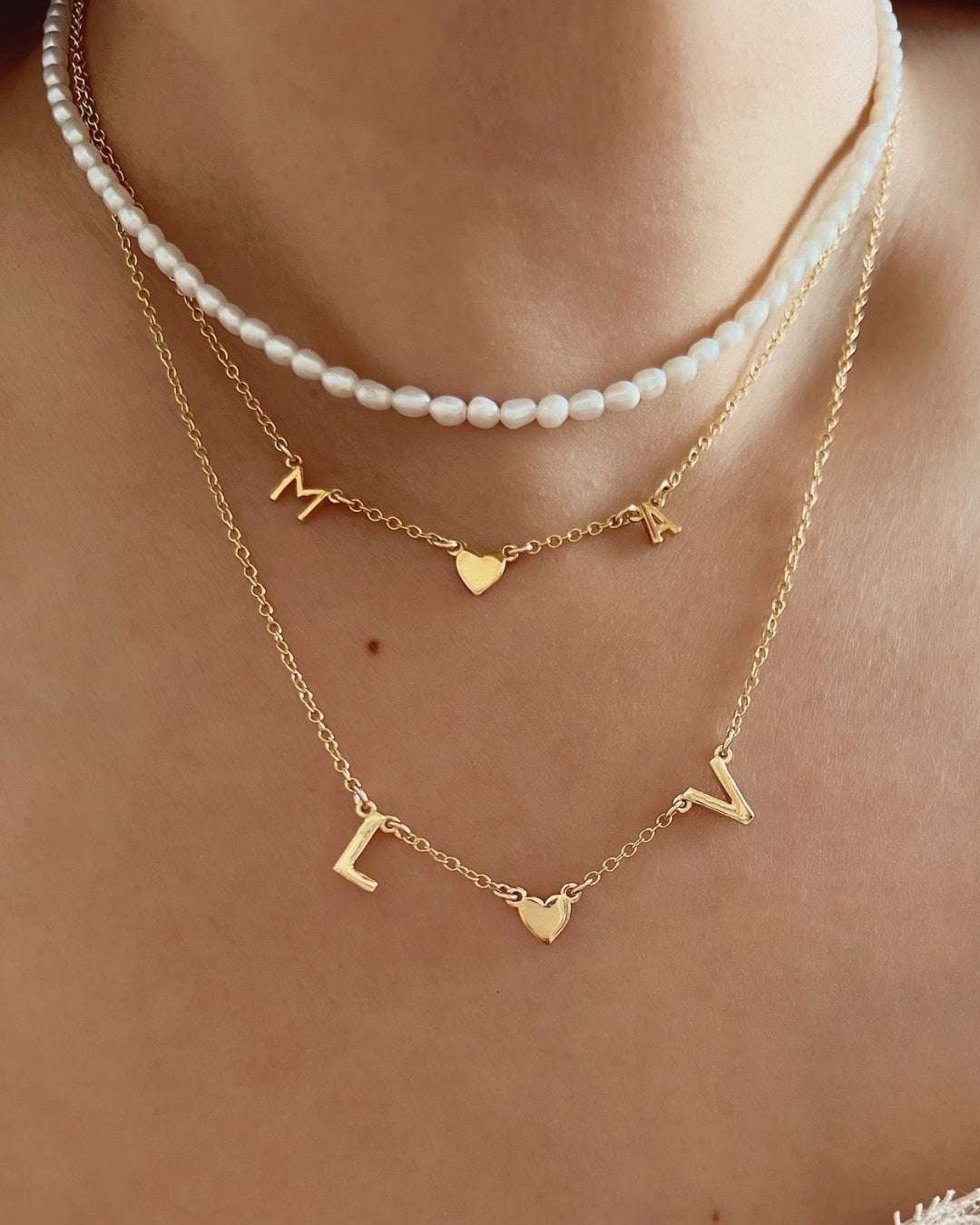 Customizable initial necklace with the option to add up to 7 letters, heart gem or gold heart on a model