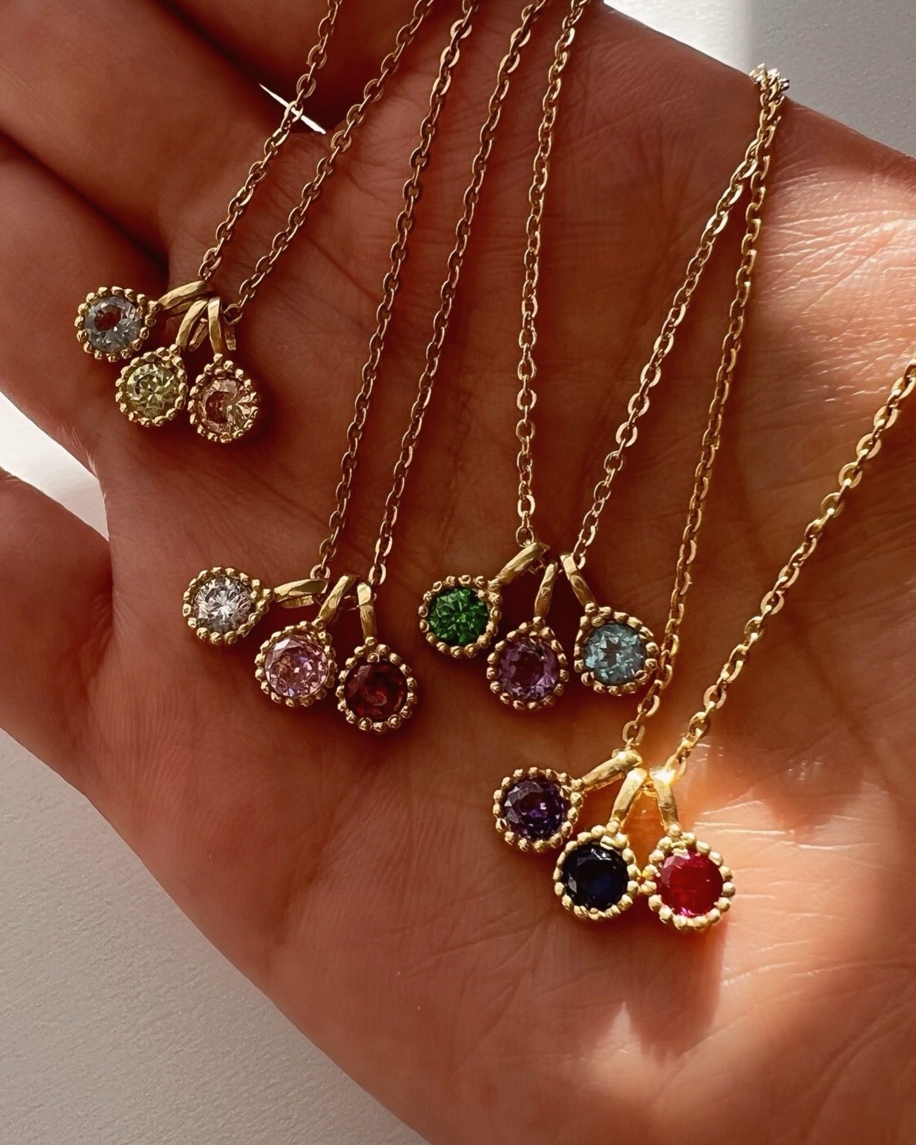 Gold Birthstone Pendants on a Necklace Chain. January Red Garnet February Purple Amethyst March Blue Aquamarine April White Diamond May Green Emerald June Lilac Alexandrite July Red Ruby August Yellow Peridot September Navy Sapphire October Pink Tourmaline November Orange Citrine December Blue Topaz