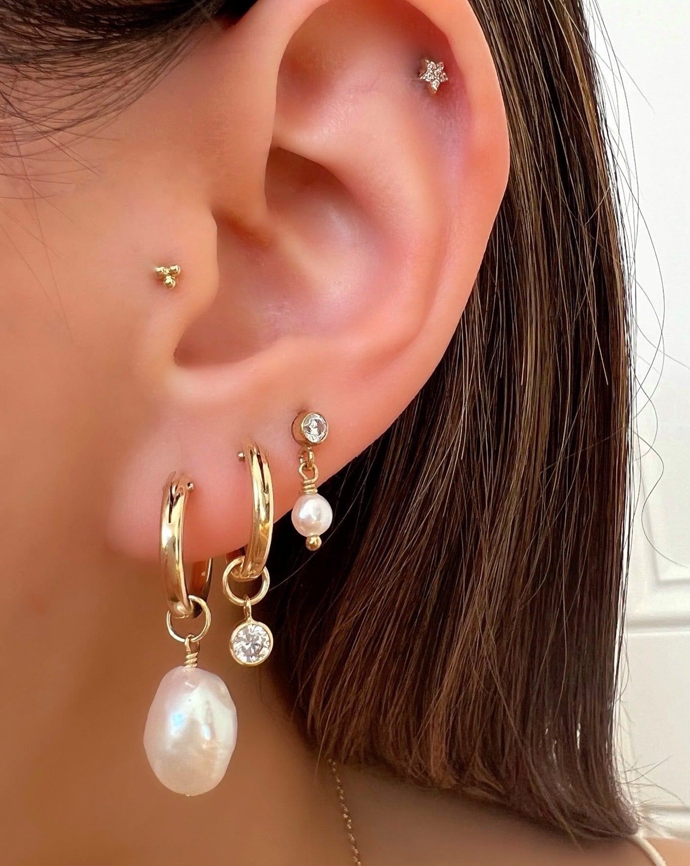 Gold freshwater pearl earring charm on gold fill hoops on a model