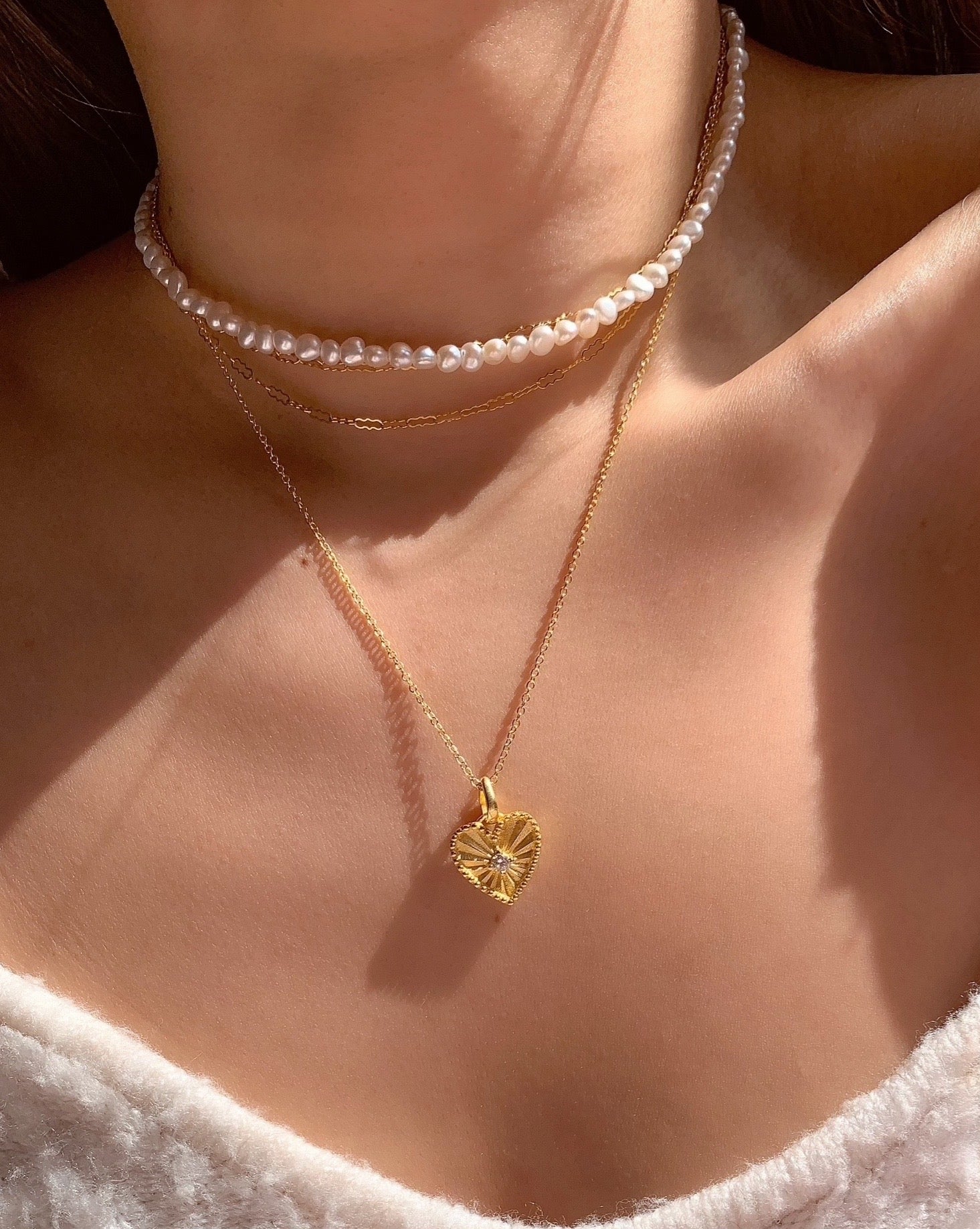 Gold love heart token pendant on gold fill necklace chain on a model