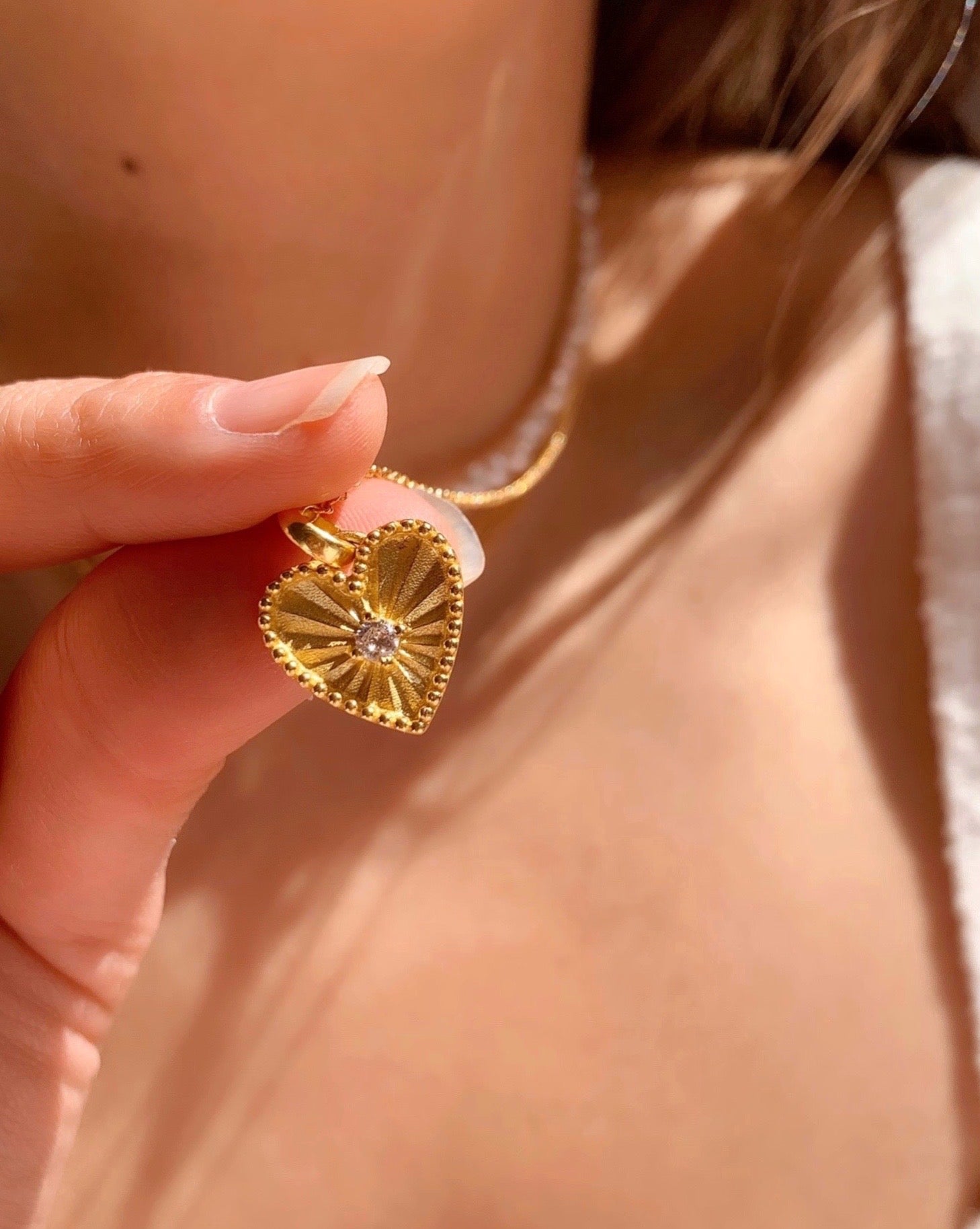 Gold love heart token pendant on gold fill necklace chain on a model