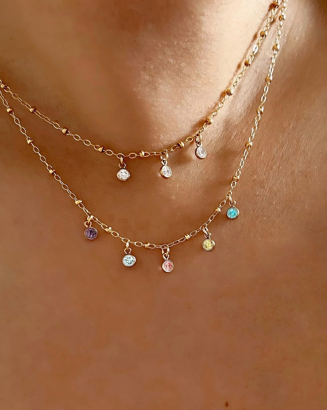 Gold fill customisable petite birthstone birth month necklace with the option to add up to 5 7 birthstone gems on a model