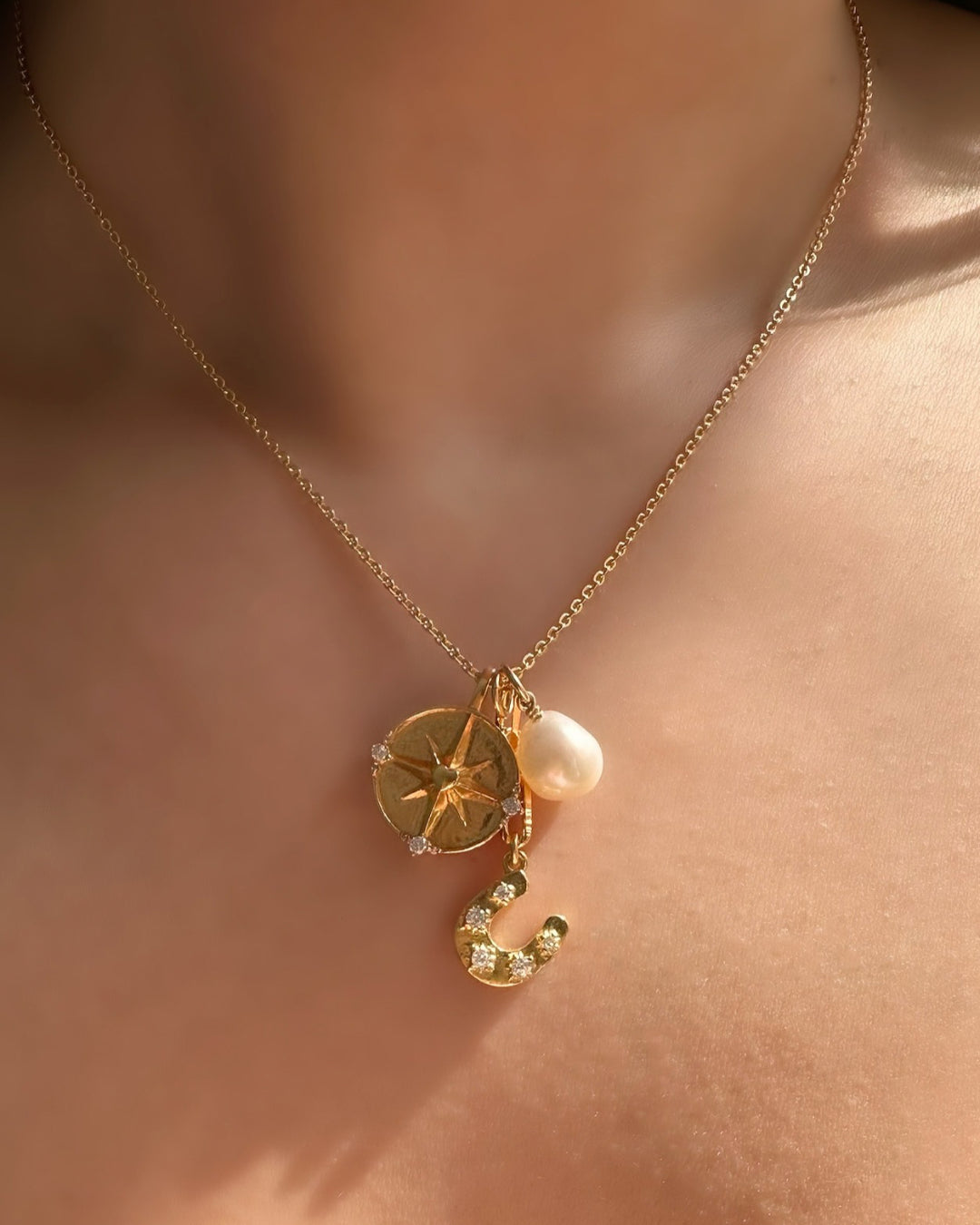 Model wearing Romyli classic pearl pendant on gold fill bail paired with classic cable chain, horseshoe talisman pendant, pendant extender and dreamers pendant – layered Australian jewellery styling.