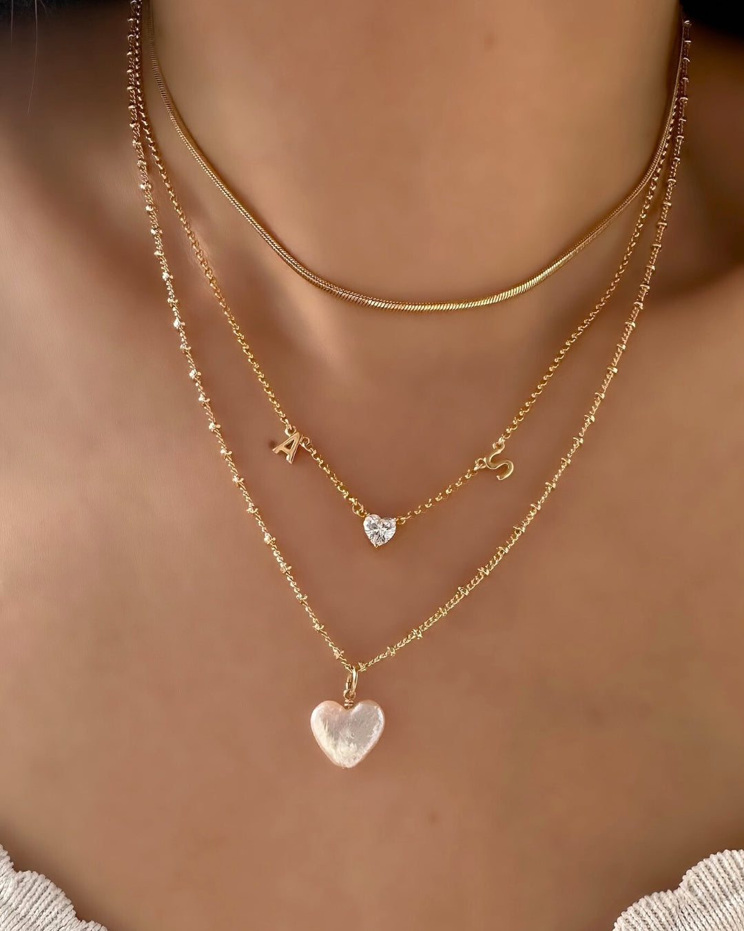 Model wearing petite initial necklace with pearl heart necklace 