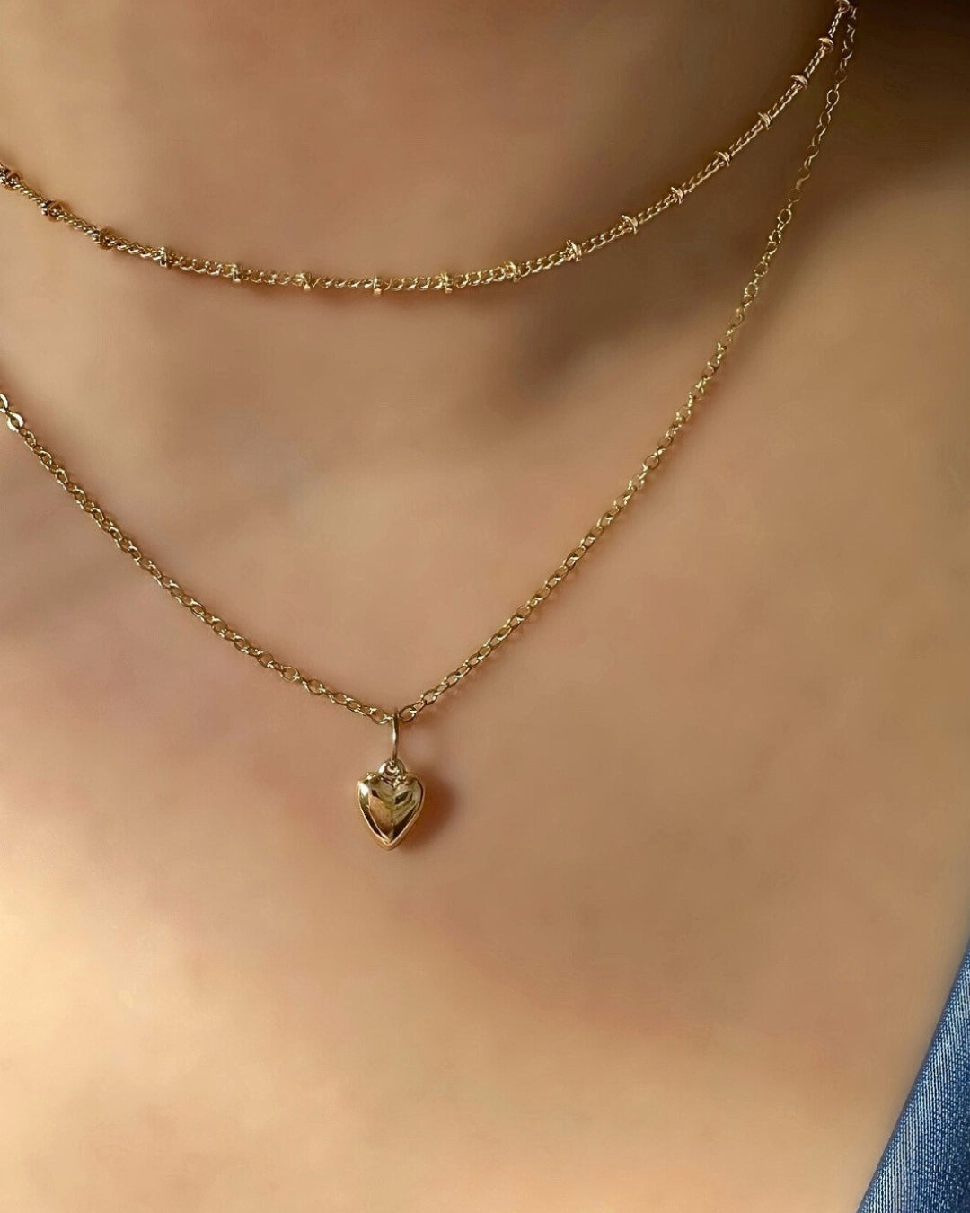 14k yellow solid gold necklace chain with a petite puffy love heart necklace charm on a model 