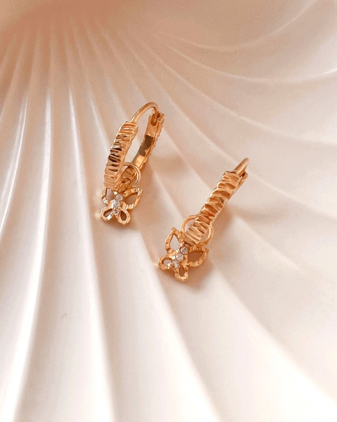 Gold ridged textured hoop earrings with gold butterfly earring charms 