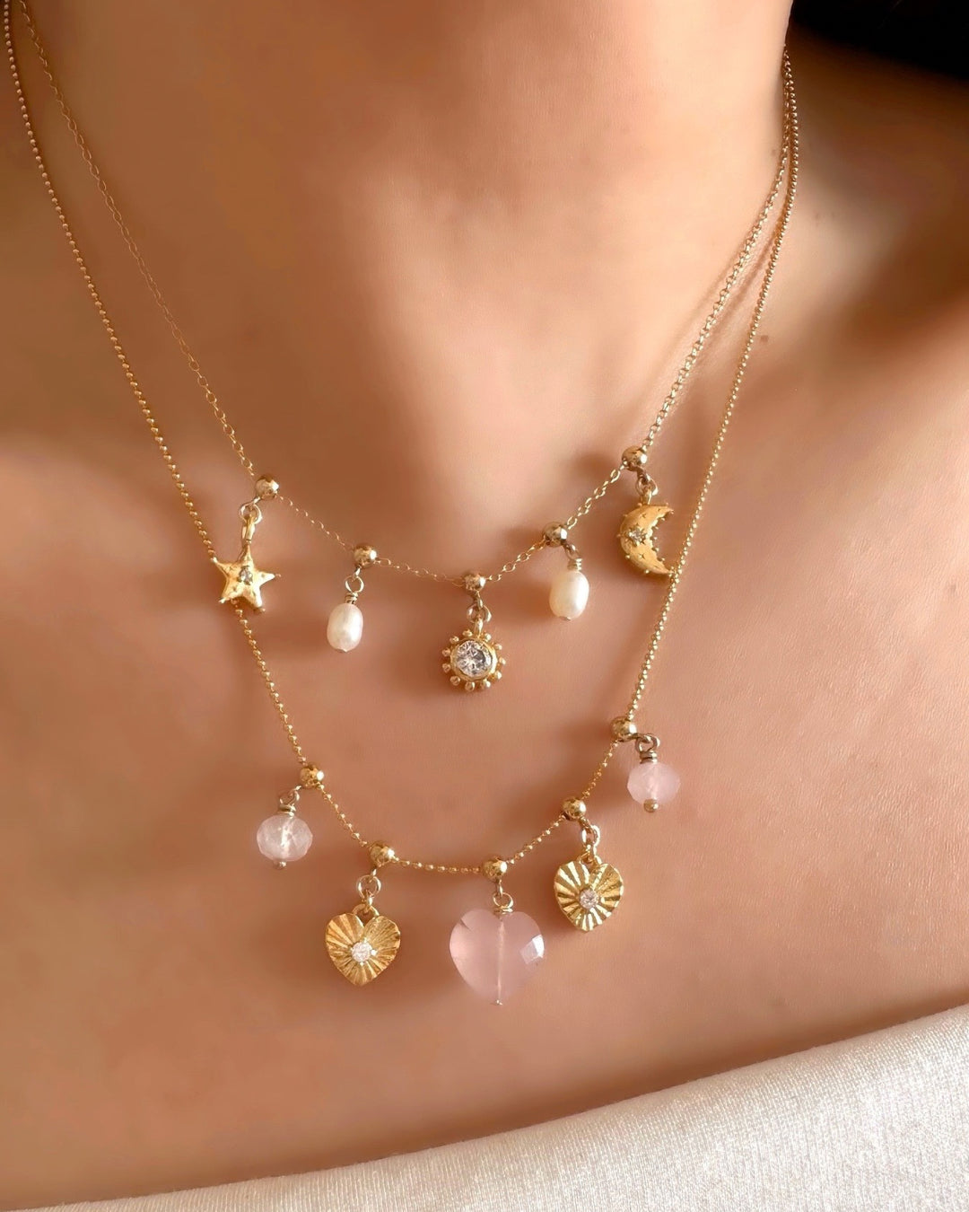 Rose Quartz Heart Charm on a Charm Story Bead Necklace, stacked with meaningful gold and semi precious charms on a model. 