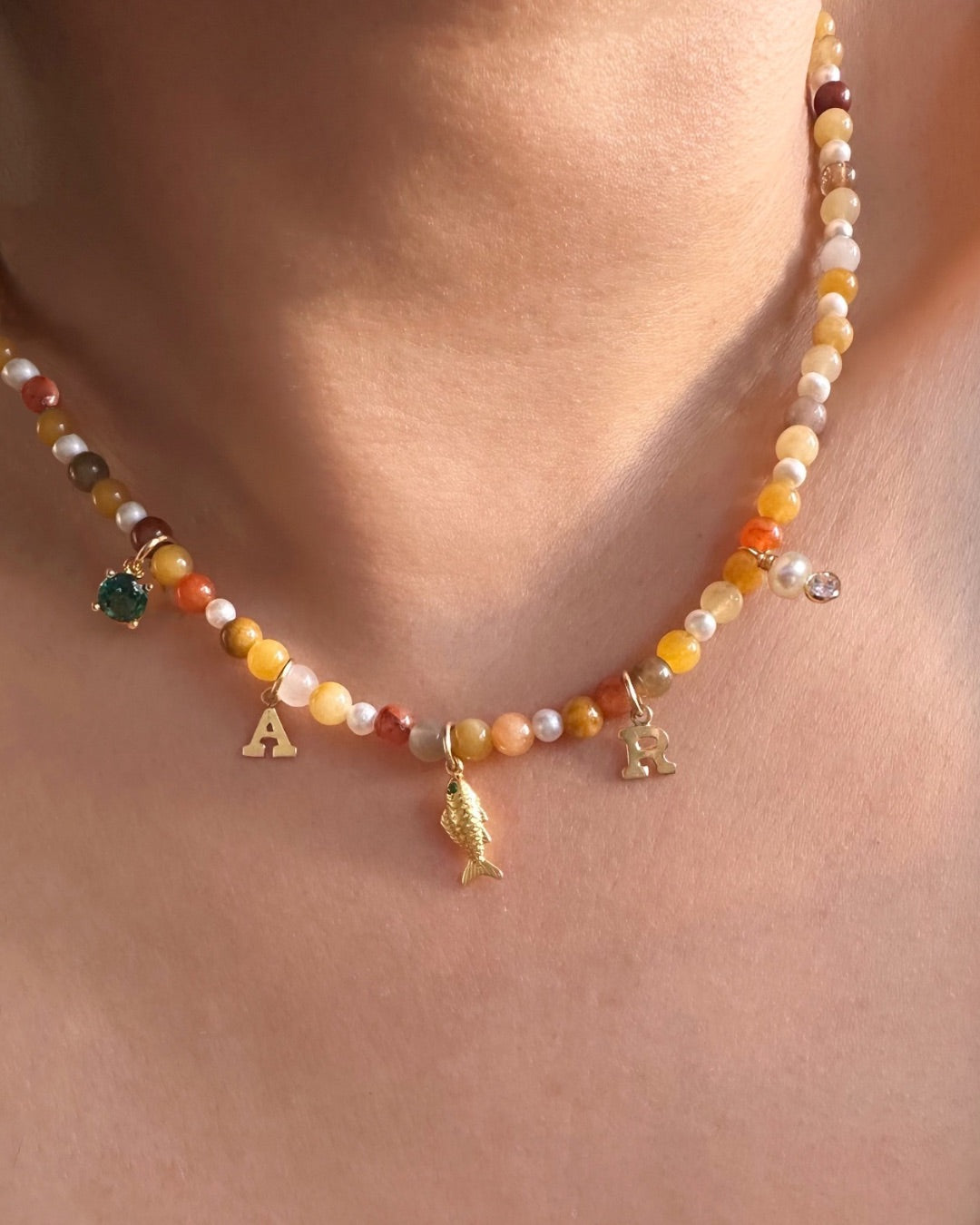 Necklace with golden Jade beads and small charms on a person's neck