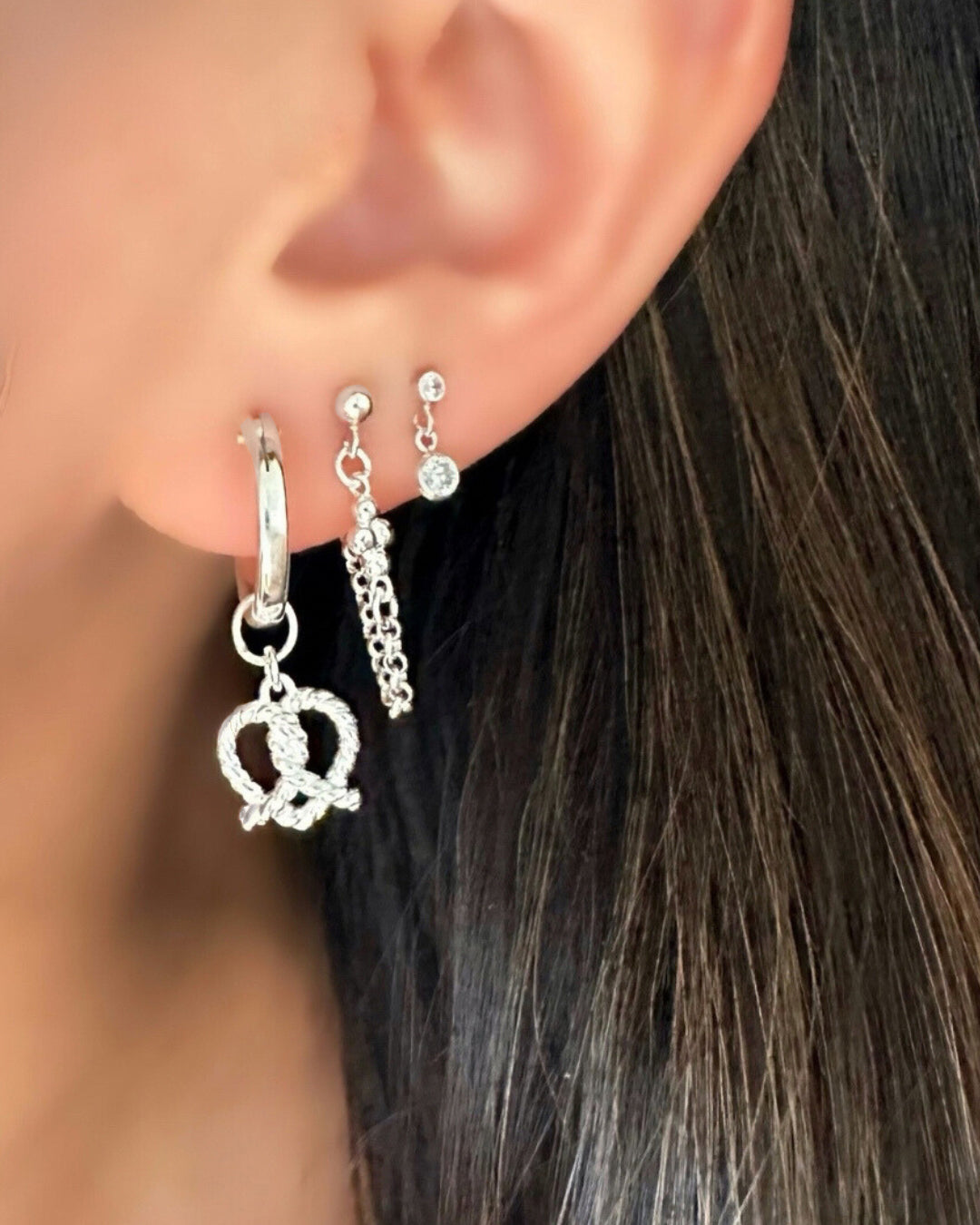 925 Sterling Silver Pretzel Heart Earring Charms on silver hoop Huggie earrings on a model