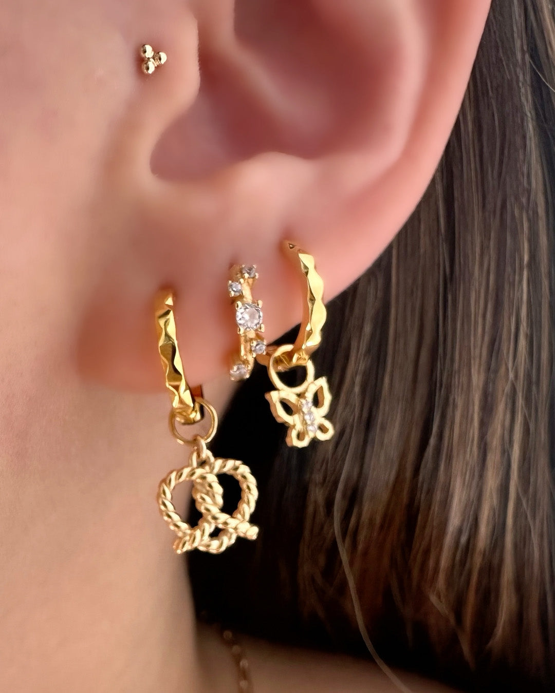 Gold Vela Hoops paired with the Pretzel Heart Earring Charm on a model