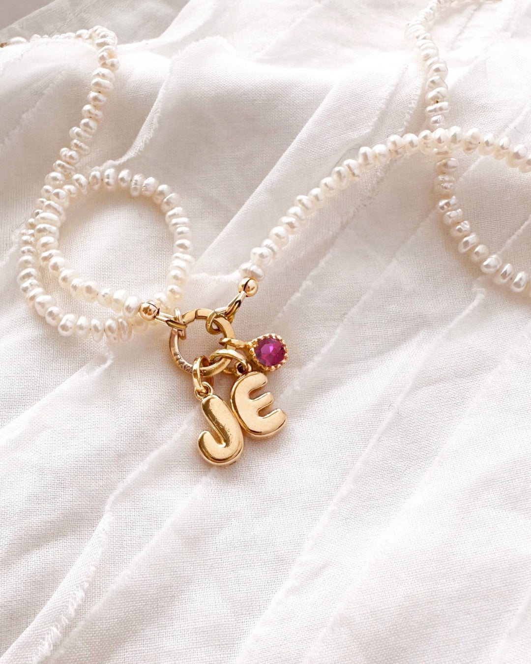 Gold Mini Pearl Charm Holder Necklace with Birthstone and Bubble Initial Pendant Charms on a white background. 