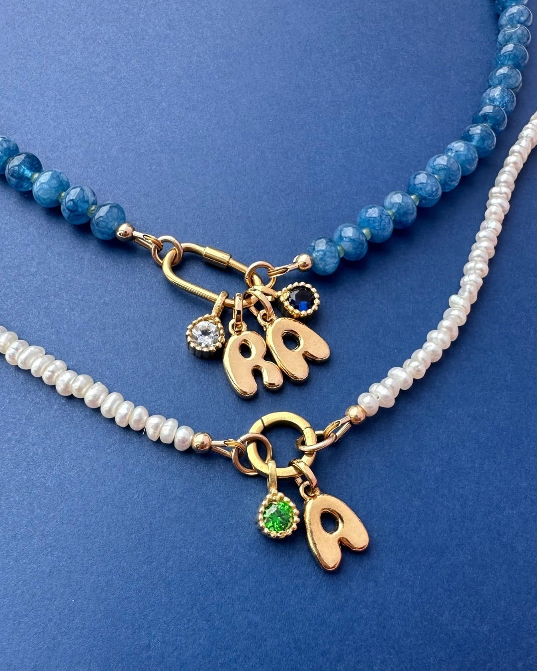Two charm holder necklaces with gold pendant charms on a blue background